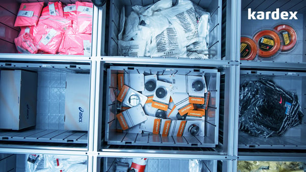 Variety of items stored in gray bins in cube storage system